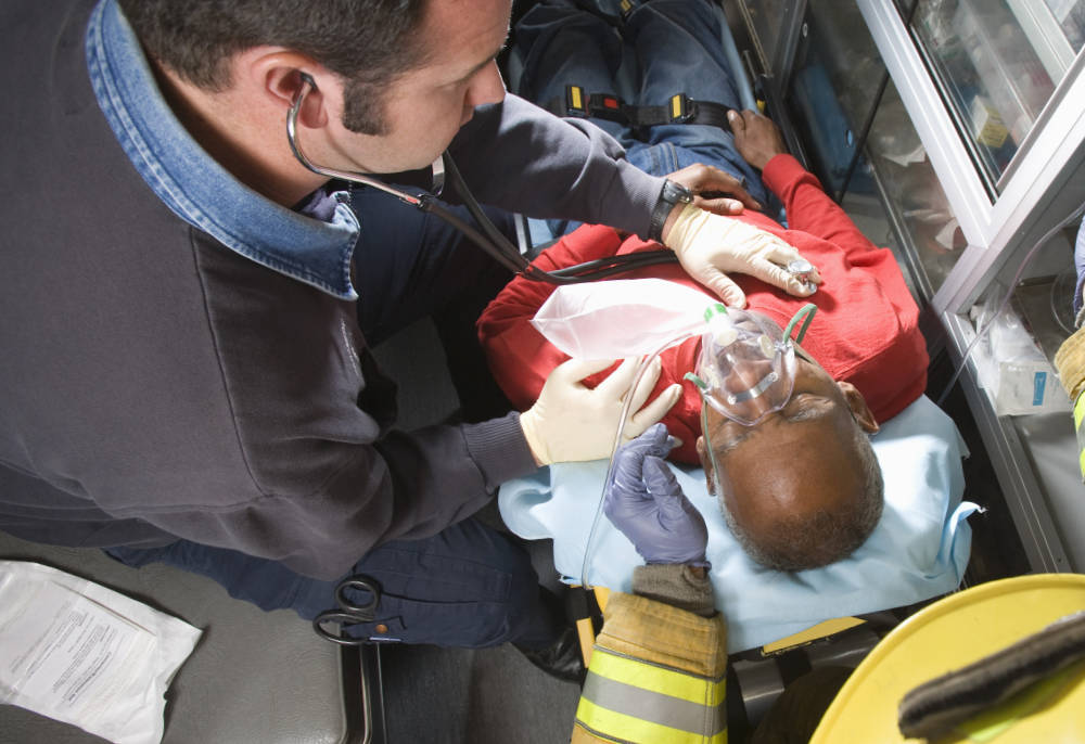 Firefighter and paramedic helping man in ambulance